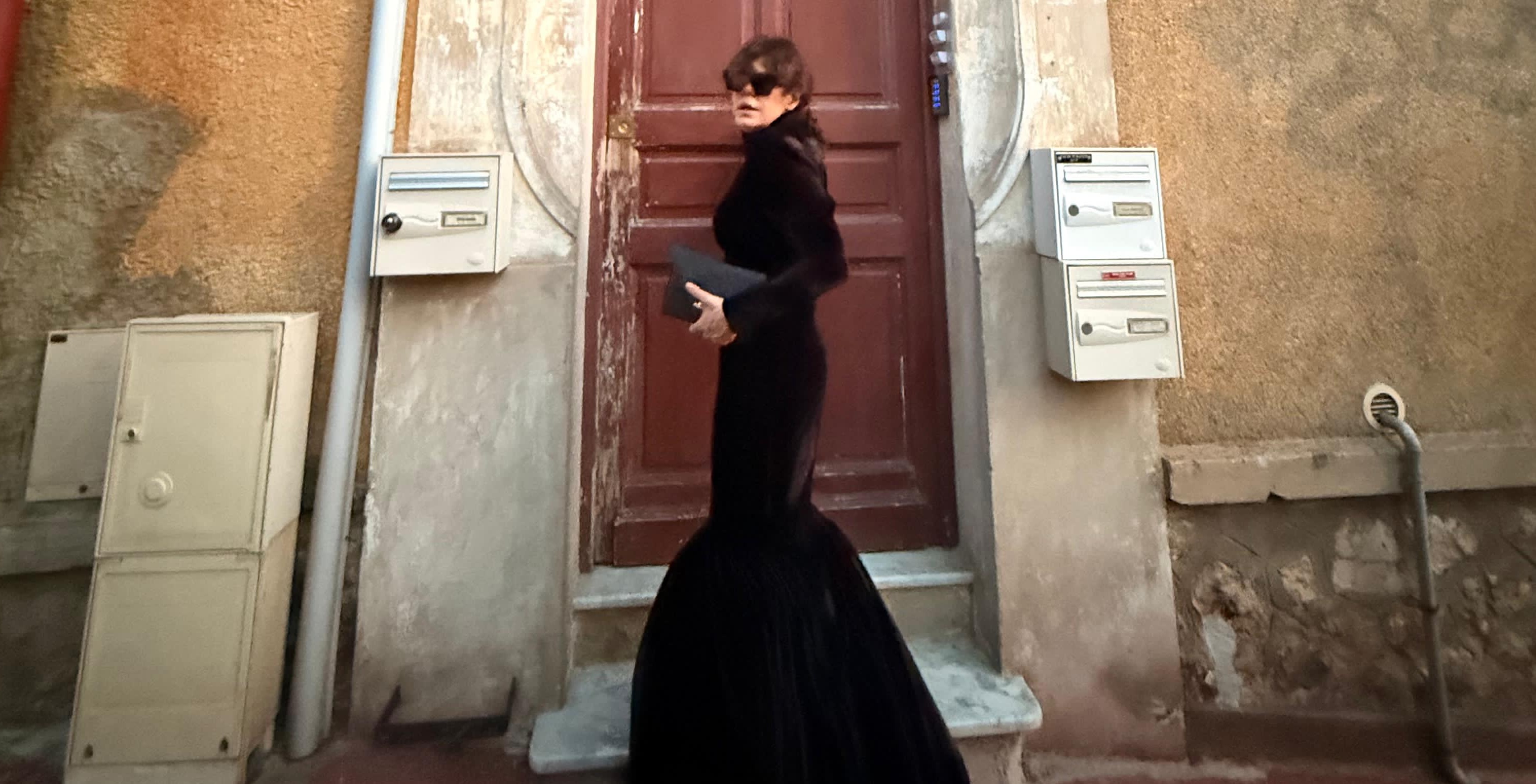 Modelo em vestido preto dramático com silhueta sereia da Forca Studio em cenário urbano europeu